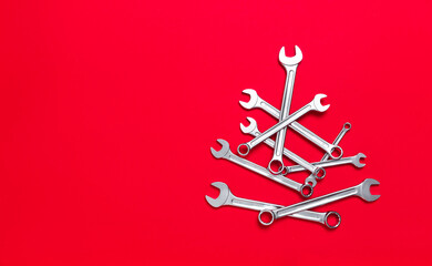 Christmas tree made of wrenches on a red background. New Year banner with tools. Postcard with place for greeting text for happy new year with industrial holiday concept. Closeup