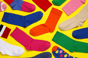 Different colorful socks on yellow background, flat lay