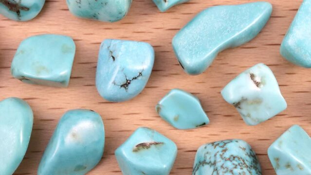 Turquoise heap up jewel stones texture on light varnished wood background. Moving right seamless loop backdrop.