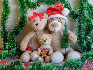 Christmas teddy bear family (two parents and a child) portrait with green tinsel