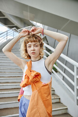 Candid portrait of young woman with curly hair looking at camera in urban city setting