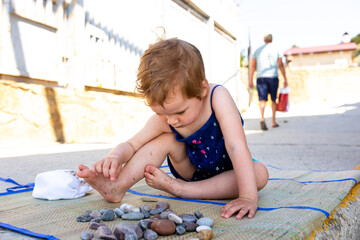 Little cute child girl playing on the seashore in summer