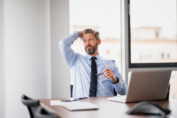 Shot of stressed businessman working with laptop at office