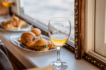 a half-full glass of cider stands by the window with snacks in the background