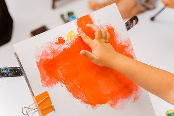 a child's hand draws with a finger on a piece of paper