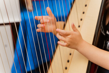 little girl's hands try to play the harp