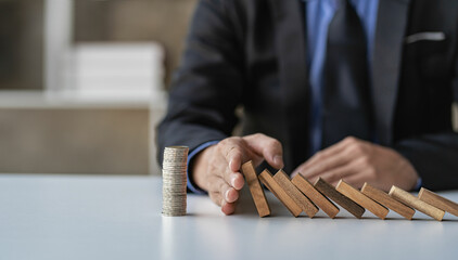 Businessman stops her hand blocking or falling dominoes Financial business and risk management...