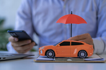 Businessman hand holding umbrella and toy car at table. Car insurance, warranty, repair. Finance,...