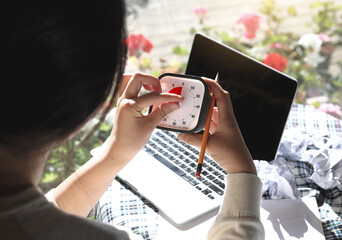A woman with an impending deadline is holding a timer and looking at it
