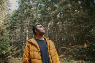 Man walking in the forest in autumn in a yellow jacket. Hiking concept.