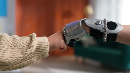 Cropped shot of woman bump fists with bionic arm