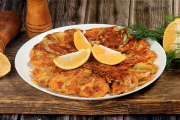 Fried small fish on a plate, decorated with lemon slices