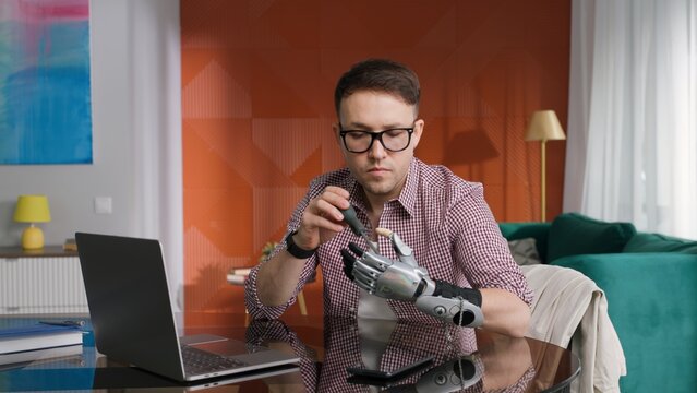 Young man with screwdriver fixing arm prosthesis at home