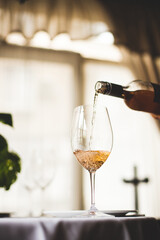 The waiter pours wine into a beautiful glass close-up. Samelie.