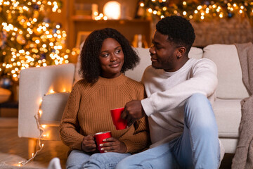 Happy young black husband and wife cheers with cups of drink, enjoy holiday and spare time