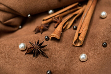 An elegant composition of spices - with anise, cinnamon on a suede brown background with beads and pearls