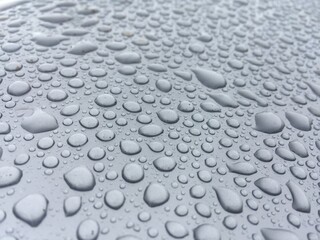 Bubble-shaped raindrops on plastic. Water background on gray plastic.