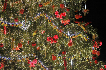 Christmas tree decorated with toys, garland and lamps on a festive street. Selective focus