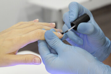 
Workplace of a manicure master. A salon specialist performs work with a client.
Nail technician wearing sterile gloves. Hand care, nail polish application. Beauty salon manicure and pedicure.