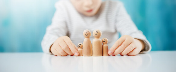 Child sitting at the table with wooden figures of the family on it.