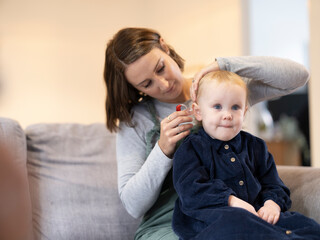 Mother helping daughter with hearing aid 