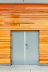 Double-swinging door in a building with wooden siding of the wall