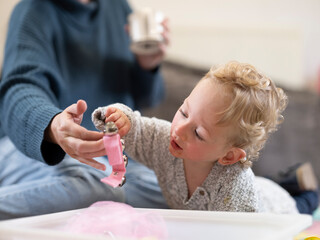 Mother hanging toy rattle to son 