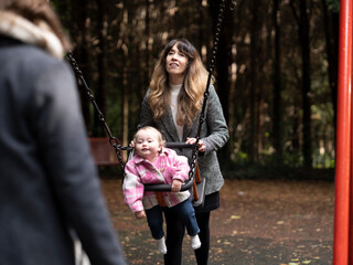 Couple swinging baby in playground at park