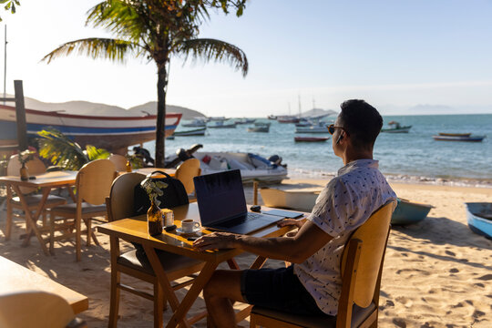 Man using laptop at beach cafe