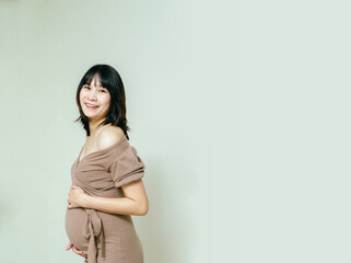 Obraz premium Pregnant happy woman touching her belly with a happy face, Caressing her belly and smiling, Healthy Pregnancy concept on white background, Copy space.
