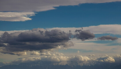 Fototapeta na wymiar Grandi nuvole nel cielo sopra le cime innevate dei monti Appennini in una giornata di sole invernale