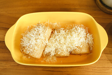 Singkong keju or fried cassava (Manihot esculenta) served with cheese topping put on yellow table