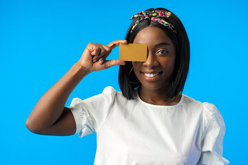 Young african woman holding credit card in hand against blue background