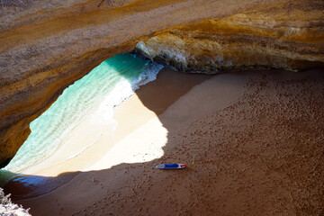 view from above into the cave of Benagil in the Algarve with paddle board on the beach                               