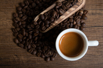 White cup of espresso with coffee beans on wooden background
