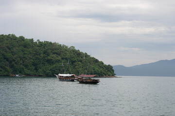 Boats in the sea of Conceição de Jacareí beach, in the background the outline of mountains and forest in Rio de Janeiro, Brazil.