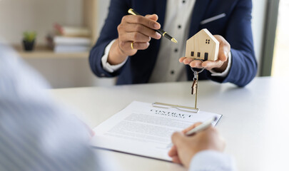 Real estate agent hands over the house keys to a homebuyer after the purchase agreement has been...