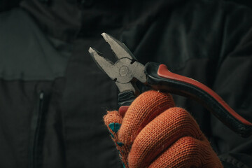 man's hand holding a black and red wire cutter plier open ready to cut form