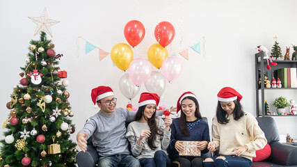 young asian man and woman celebrate Christmas eve in room decorated with Christmas tree