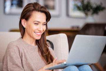 Smiling caucasian woman using laptop at home while sitting on the floor