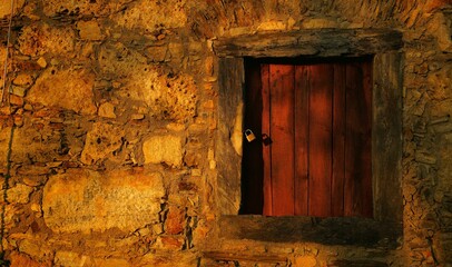 eine alte steinmauer mit einer kleinen holztür, mit vorhängeschloss, weiches licht, licht und schatten, querformat, banner, karte