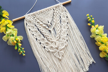 macrame wall hanging and flower on blue background
