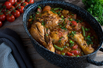  Stew with chicken, vegetables, potatoes and legume in a rustic pot on wooden table