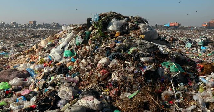 Closeup of burning trash piles in landfill with people recycling trash