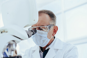 close up. a serious scientist using a laboratory microscope.