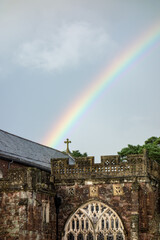 detail of a church with rainbow against a dark cloudy sky