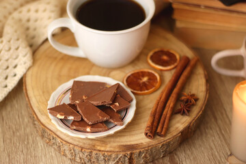 Bowl of cookies, cup of tea or coffee, chocolate, spices, knitted blanket, books, glasses and candle on the table. Cozy hygge atmosphere at home. Selective focus.