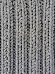 Gray knitted texture. Elastic knitting pattern close up. Needlework hobbies. 