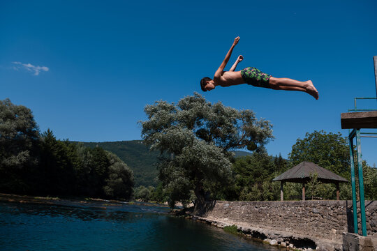 young man prepare to jump into the water of the clean river, swims, enjoys spending time on summer holidays.