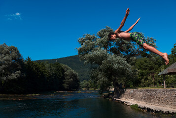 young man prepare to jump into the water of the clean river, swims, enjoys spending time on summer holidays.
